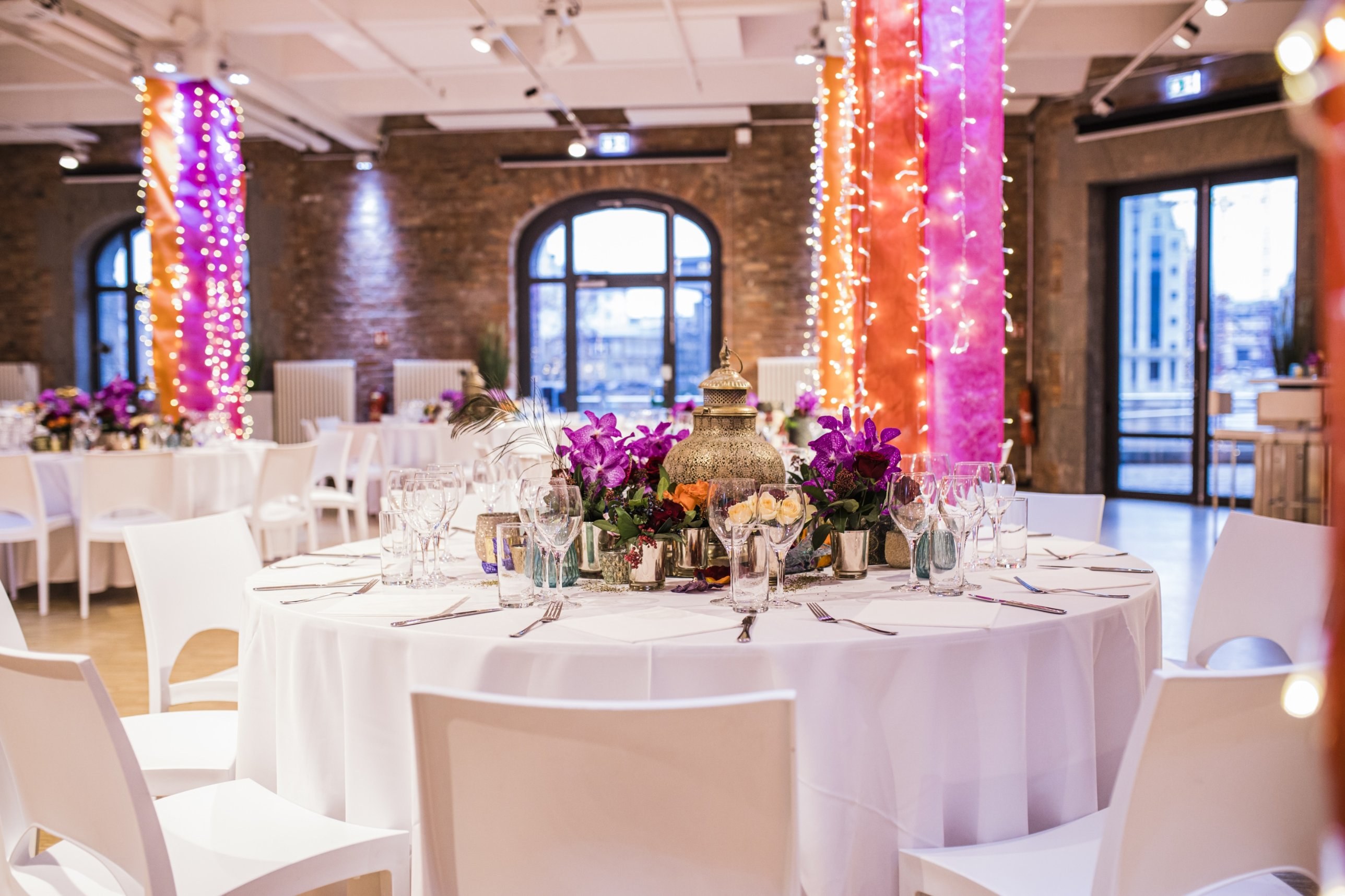 030 Eventloft Grande mit rundem Weihnachtstisch und Lichterketten an den Säulen
