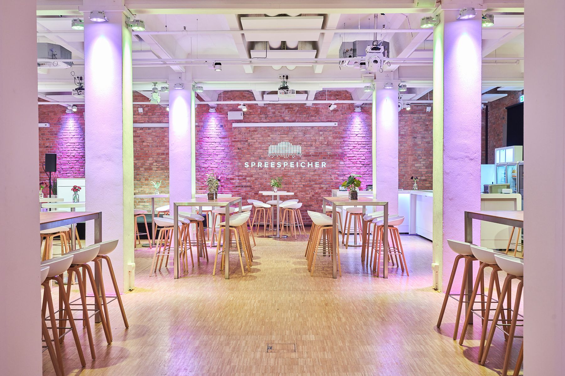 Standing tables between columns under purple lighting