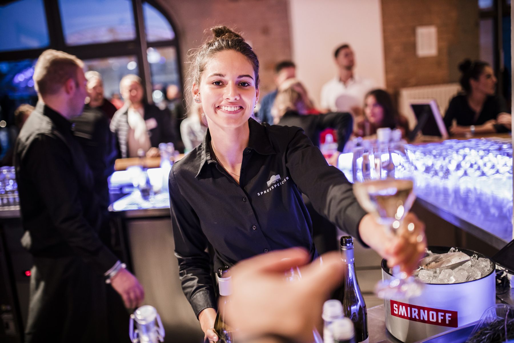 Service staff member holding drinks in front of event guests